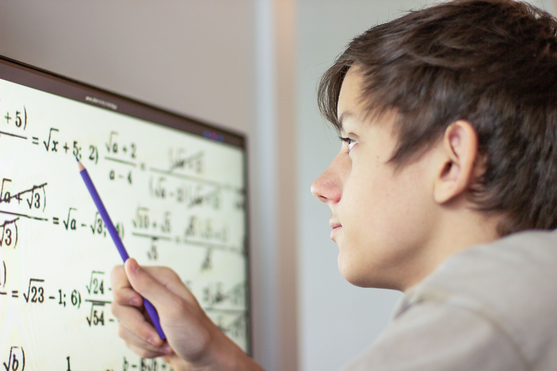 A student solves math problems on a computer. a teenage boy is studying online